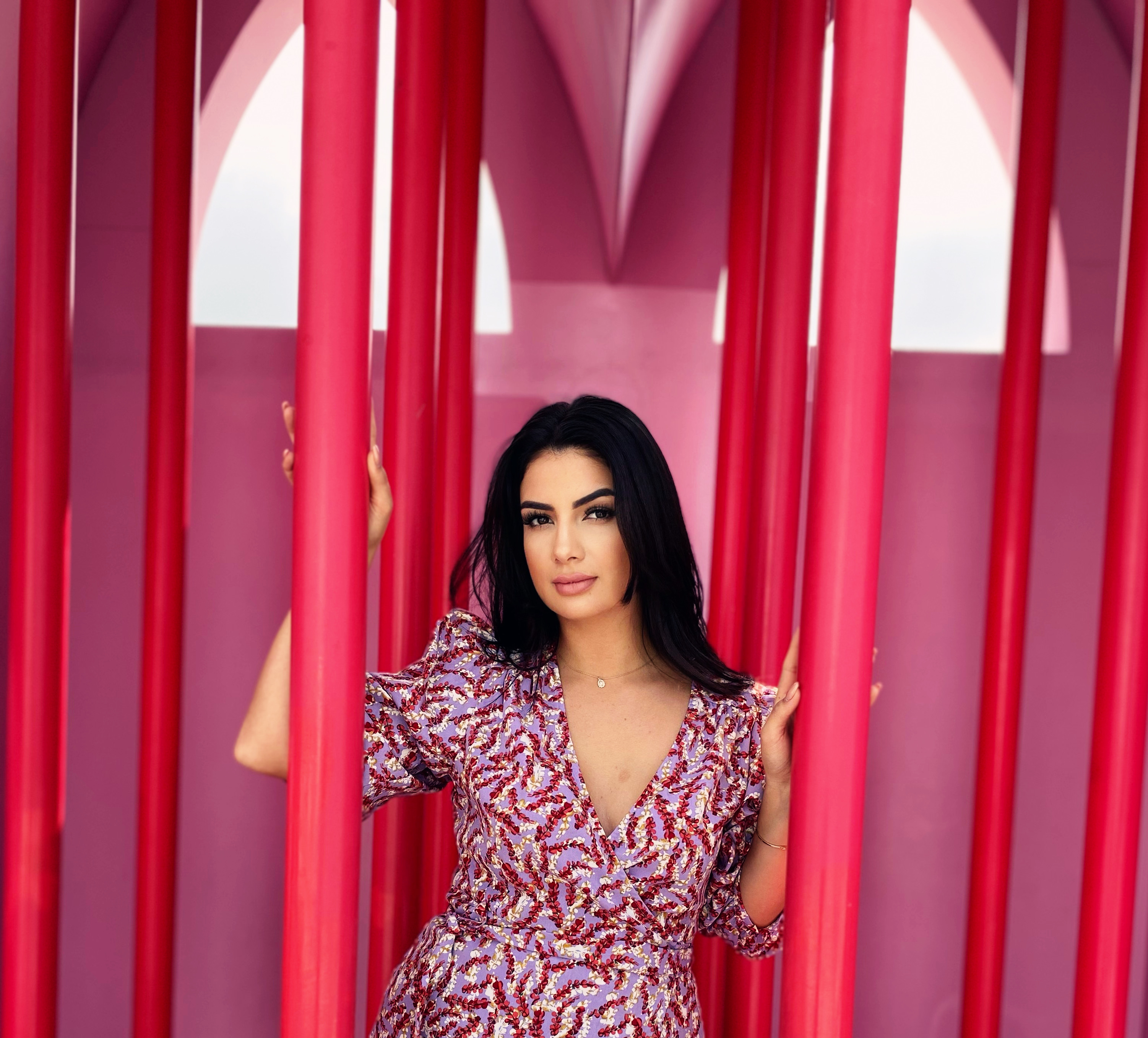Sobia Mohammed in einem geblümten Kleid zwischen pinken Säulen